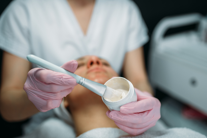 Doctor in gloves rubs the cream on patient face